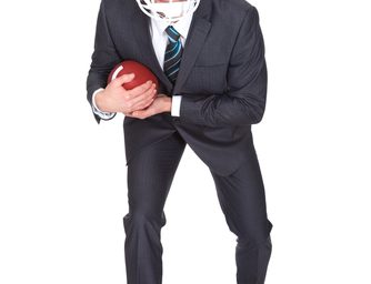 Fuehrungskraft mit Football und Schutzhelm in Startposition Fuehrungskraft mit Football und Schutzhelm in Startposition